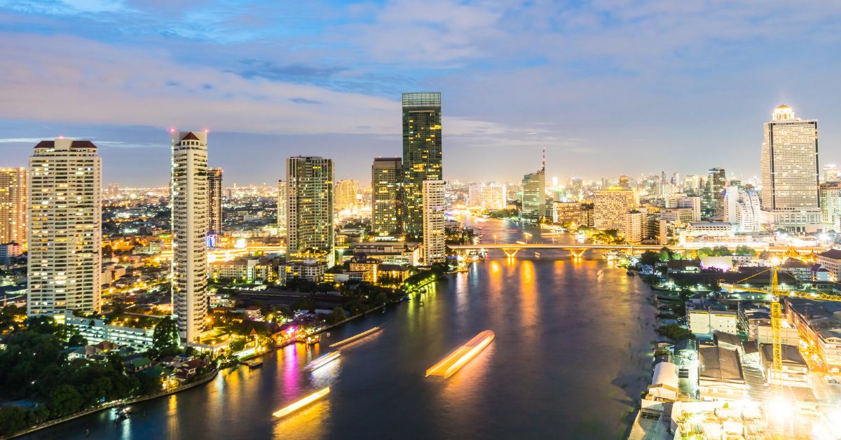 A night view over Chao Praya river, with the night light of city scape contrast to the dark blue and orange evening sky.